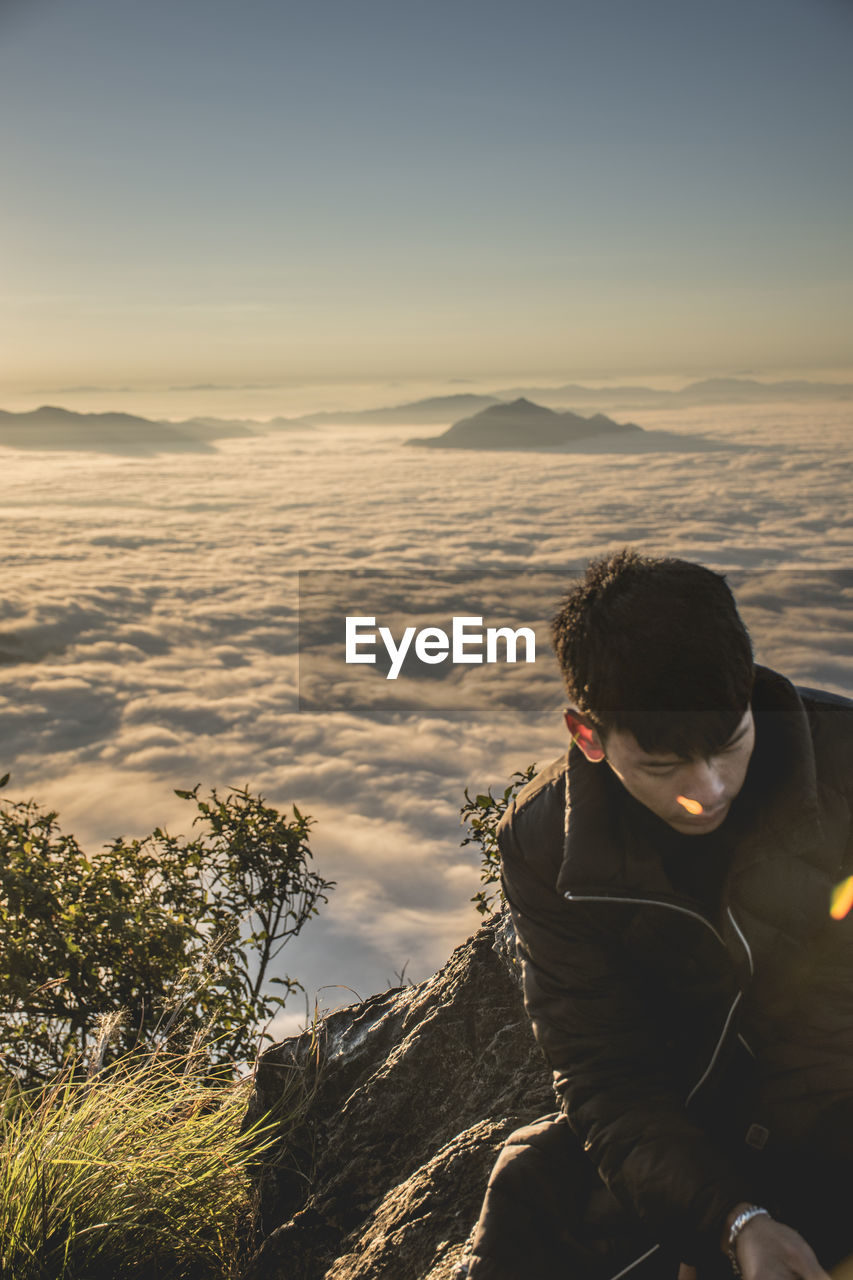 REAR VIEW OF MAN LOOKING AT MOUNTAIN RANGE