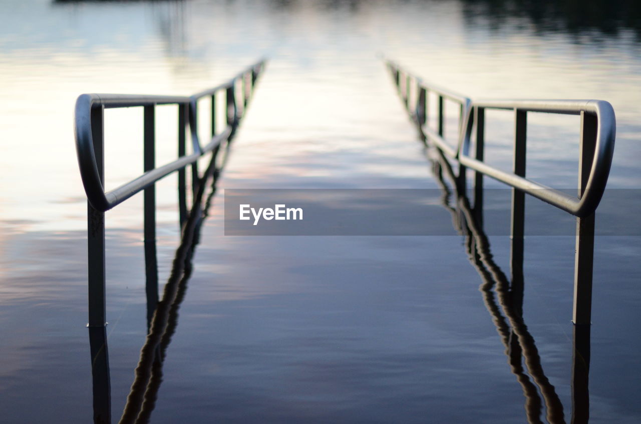 Close-up of railing in lake at sunset
