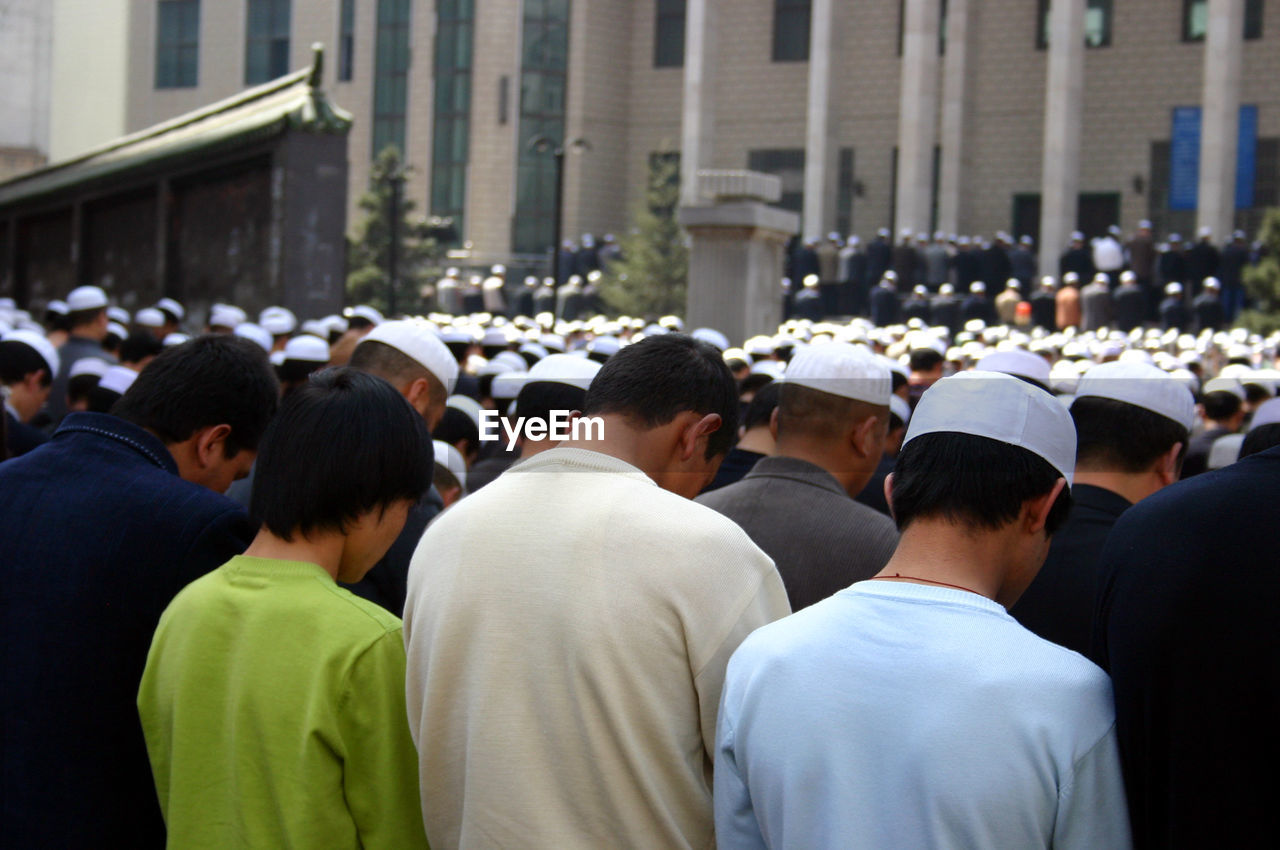 Rear view of crowds praying outside mosque