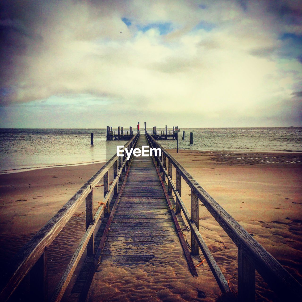 VIEW OF WOODEN PIER ON BEACH AGAINST SKY