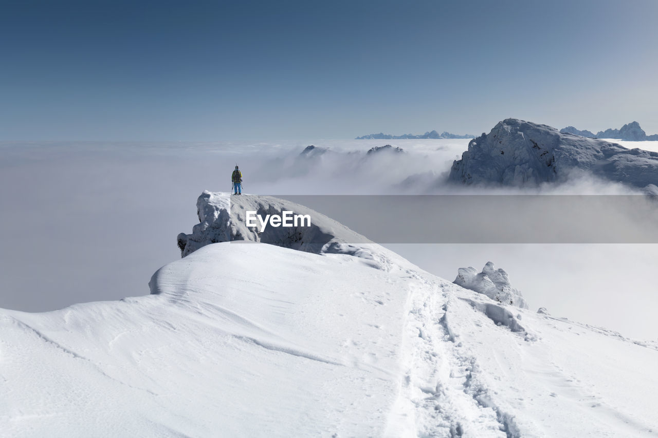 Person standing on snowcapped mountain against sky