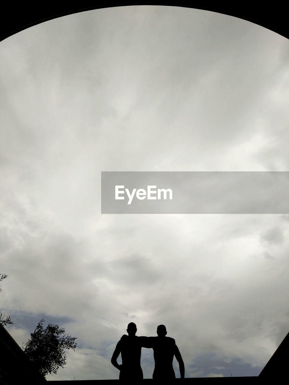 LOW ANGLE VIEW OF TWO PEOPLE STANDING ON TOP OF RAILING