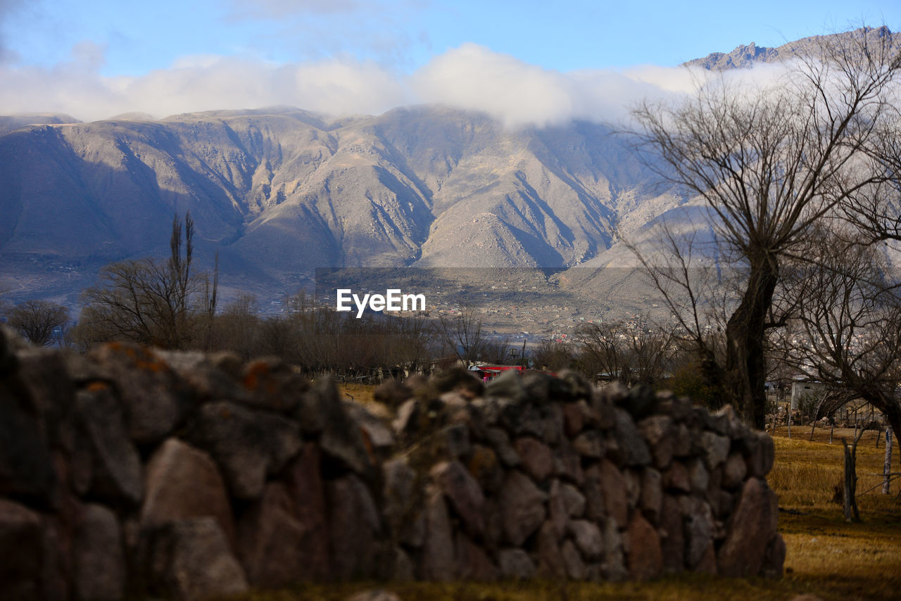 Stone wall on field with mountains in background