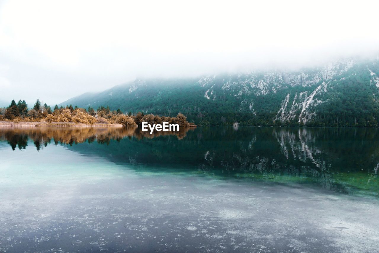 Scenic view of lake by mountains against sky