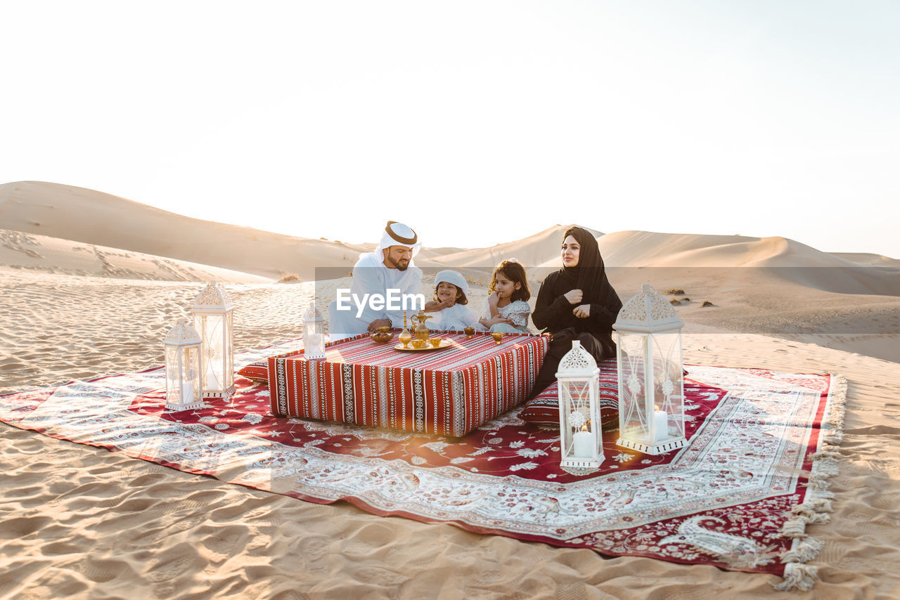 Happy family sitting carpet at desert