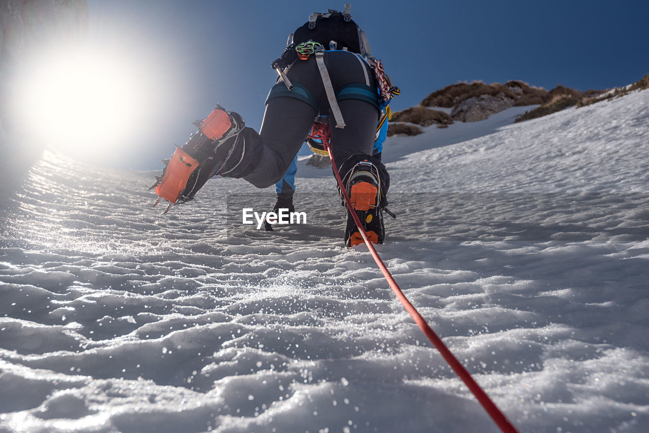 Low angle view of woman climbing snow covered mountain