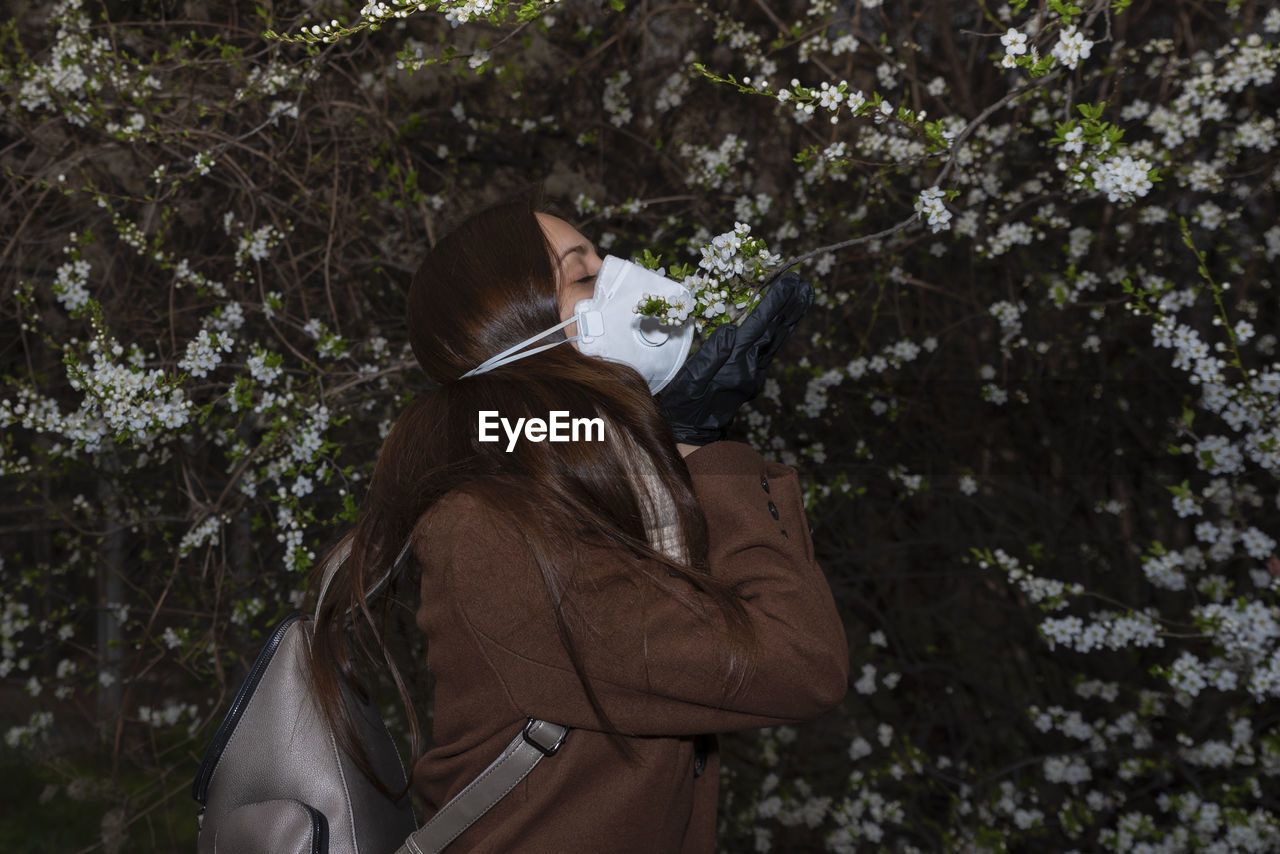 Rear view of woman holding umbrella against trees