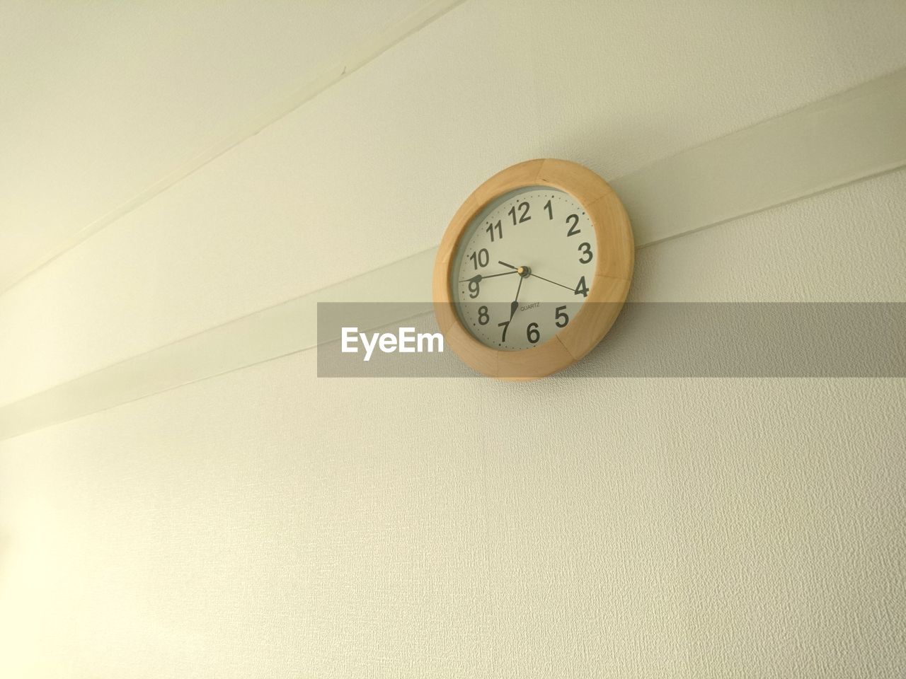 LOW ANGLE VIEW OF CLOCK MOUNTED ON WALL IN ROOM