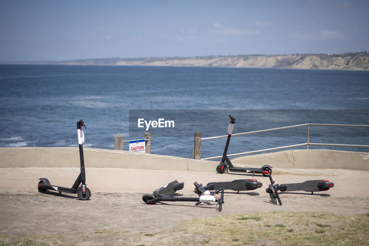 Four abandoned electric scooters, la jolla cove overlooking ocean