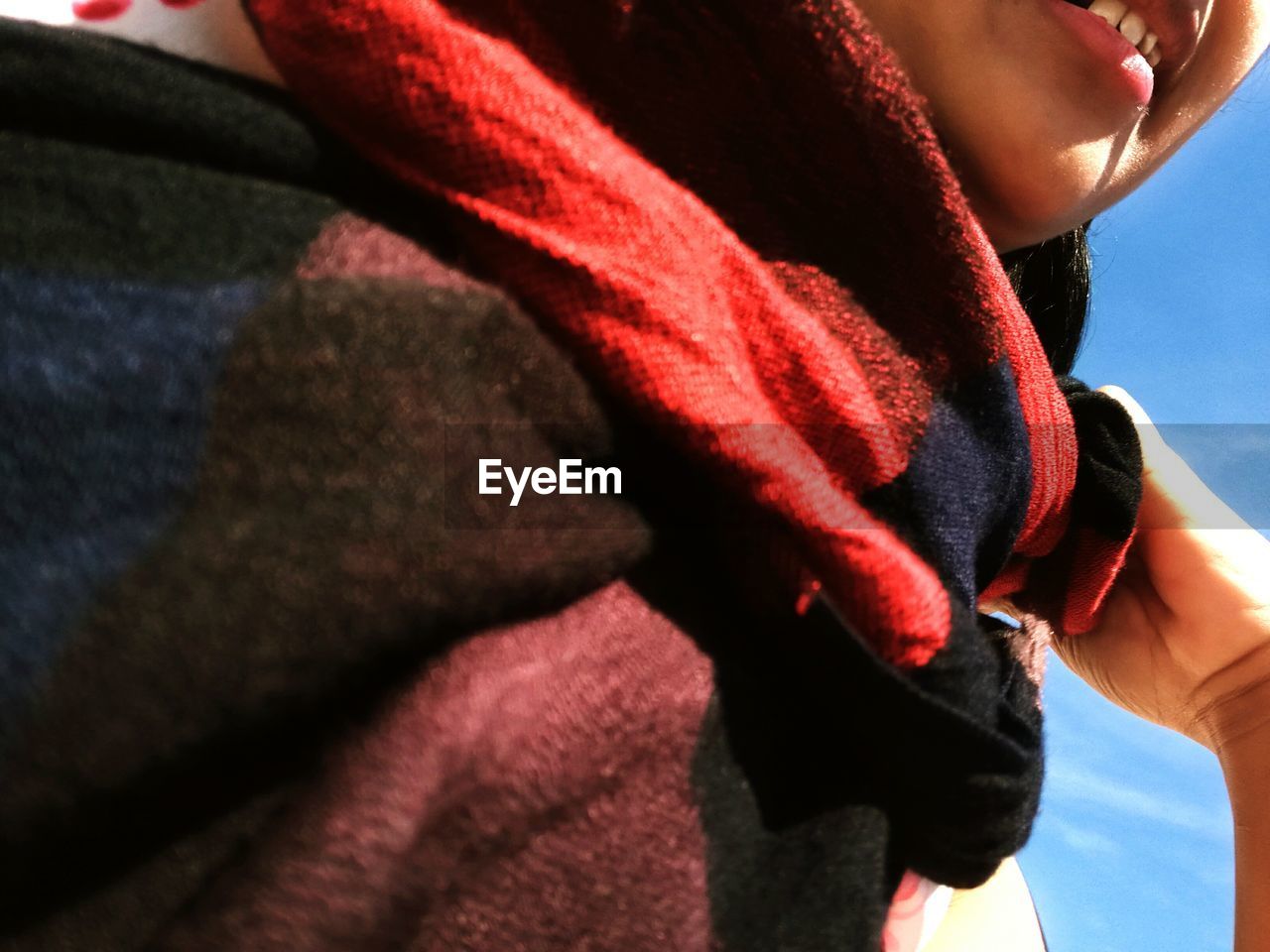 Close-up of woman holding scarf against sky