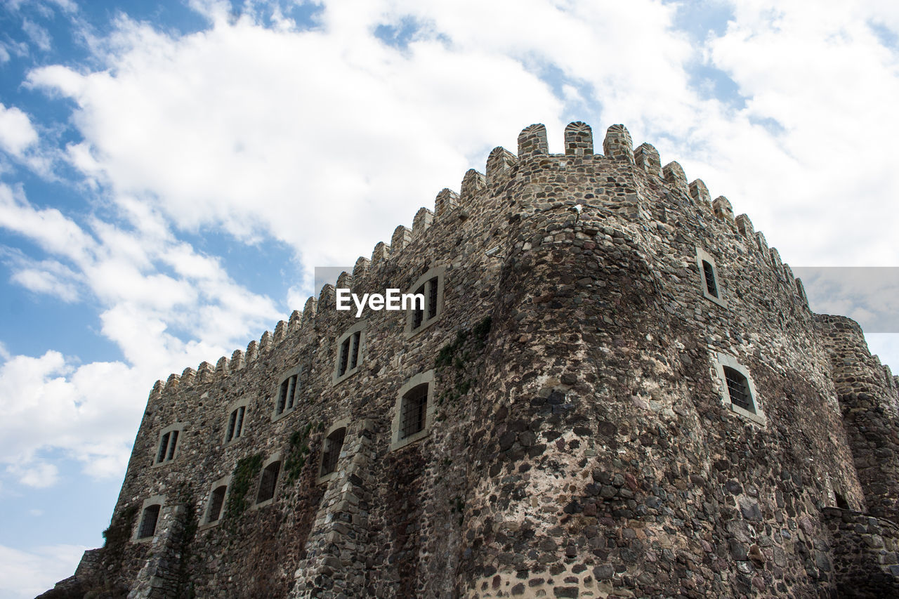 Low angle view of fortified wall against cloudy sky