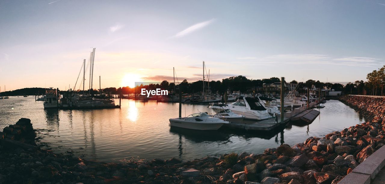 Boats moored at harbor against sky during sunset