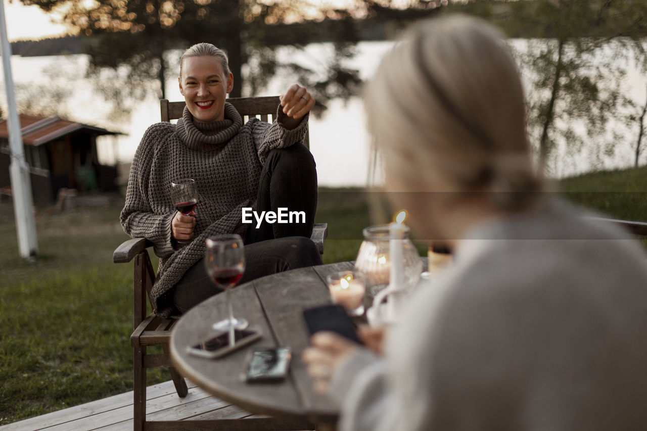 Female friends sitting on porch and drinking wine
