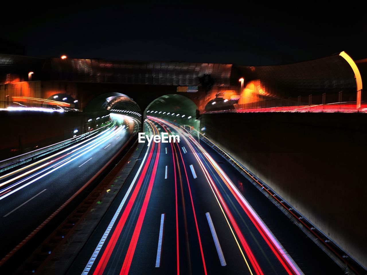 light trail, motion, long exposure, night, illuminated, speed, transportation, architecture, city, tail light, light, traffic, blurred motion, road, mode of transportation, street, darkness, built structure, city life, highway, no people, building exterior, motor vehicle, lighting equipment, car, headlight, on the move, travel destinations, light - natural phenomenon, outdoors, travel, red, multi colored, nature, city street, the way forward, street light, sign, infrastructure