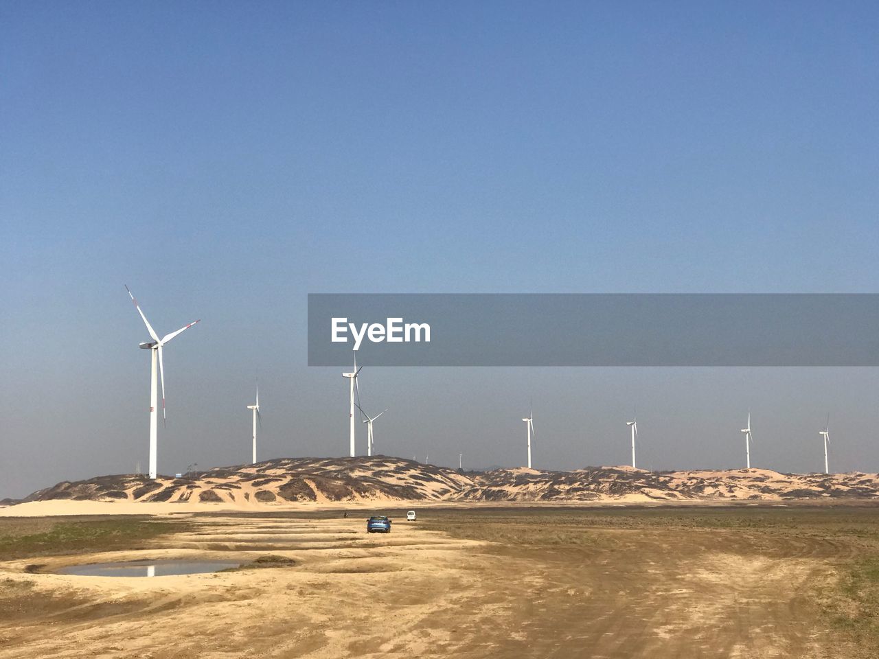 Windmills on field against clear blue sky