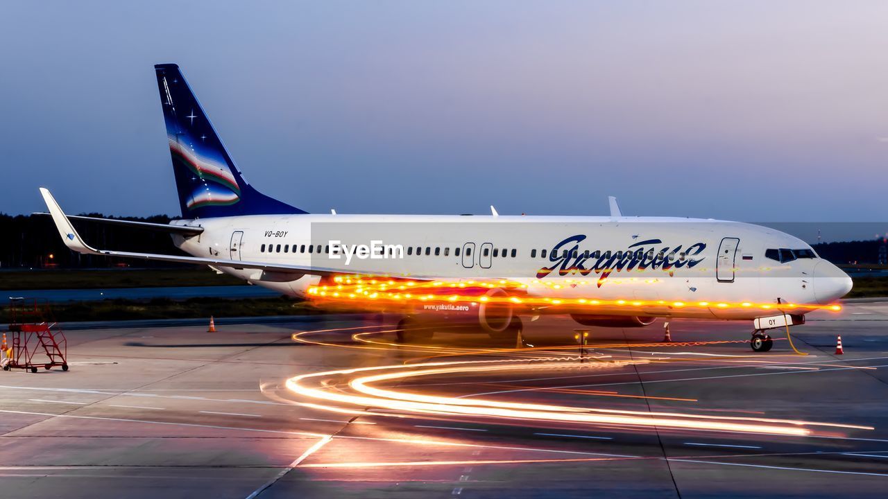 AIRPLANE AT AIRPORT RUNWAY AGAINST SKY