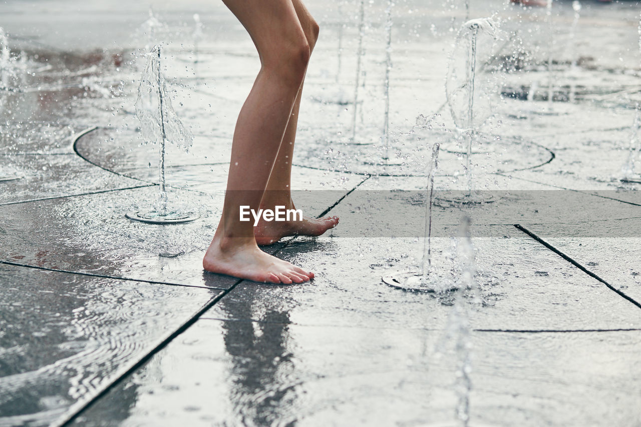 Low section of person jumping at water fountain