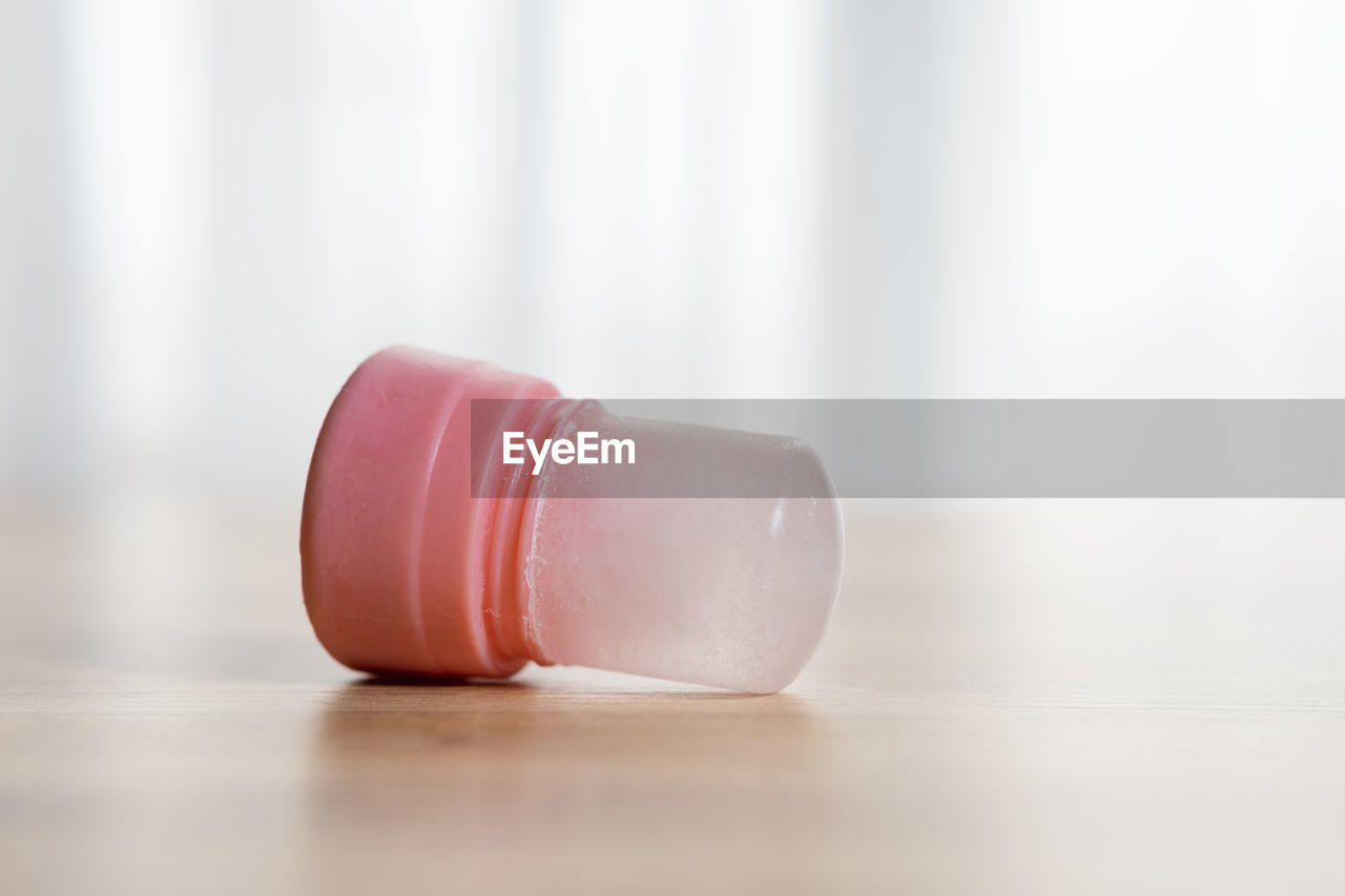 CLOSE-UP OF BOTTLE IN GLASS ON TABLE