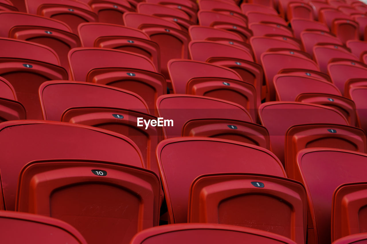 Empty red plastic seats in an empty stadium. many empty seats for spectators in the stands.