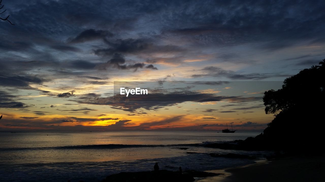 SCENIC VIEW OF BEACH AGAINST DRAMATIC SKY