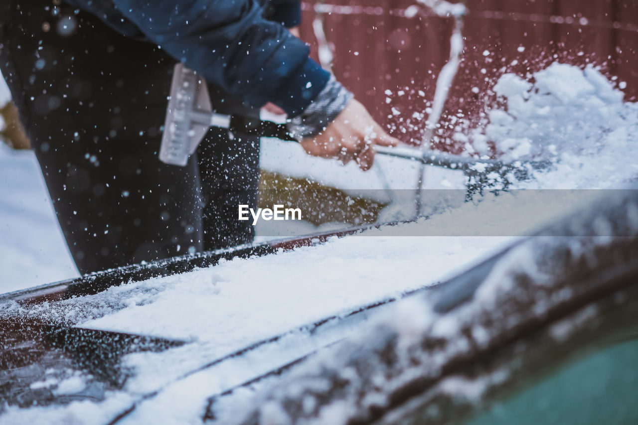 Young teen cleaning snow from the car hood