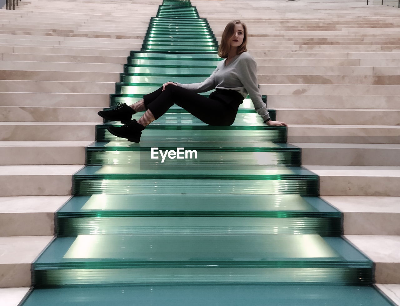 YOUNG WOMAN SITTING ON STAIRCASE