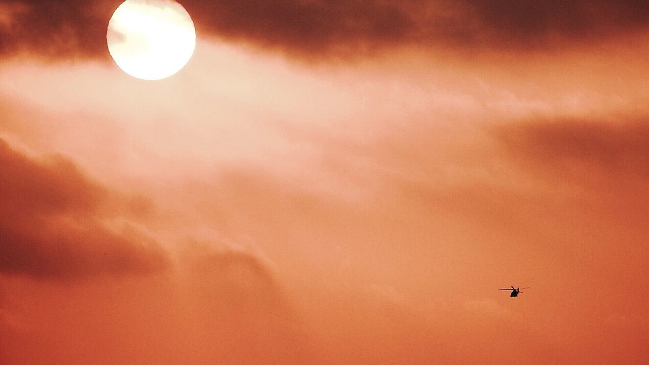 Helicopter flying against orange sky during sunset