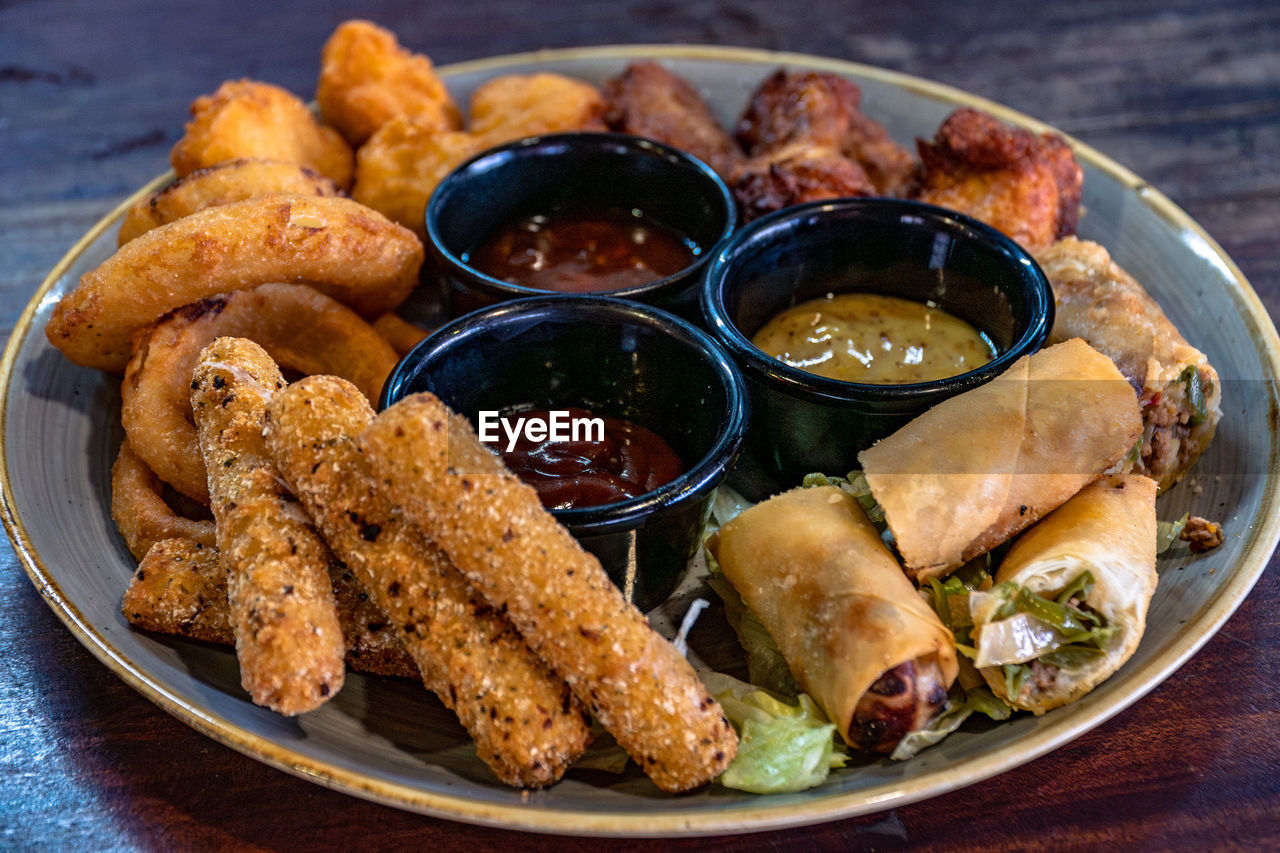 A close up image of a mixed appetizer combo platter served with dipping sauces.