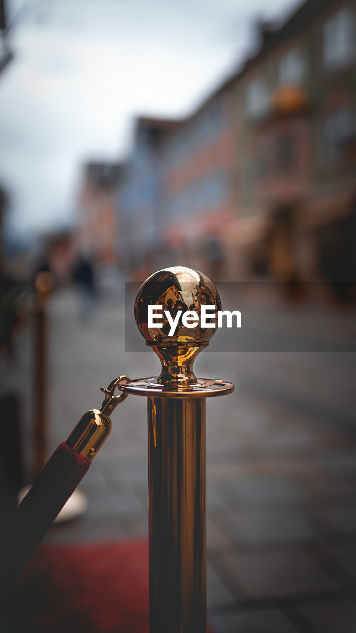 Close-up of metal railing against buildings in city