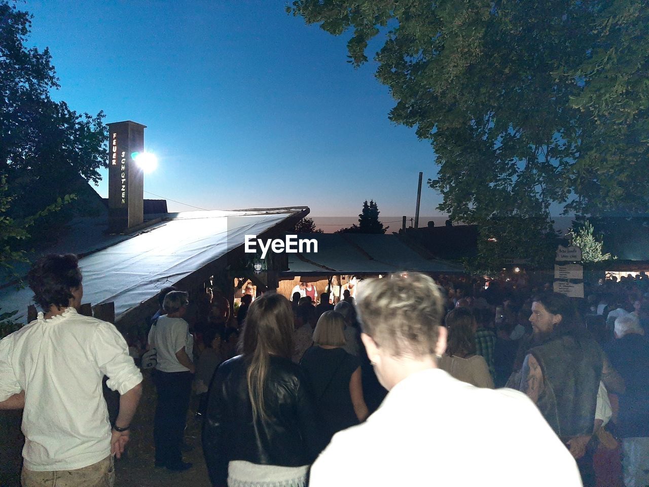 REAR VIEW OF PEOPLE IN FRONT OF BUILDINGS