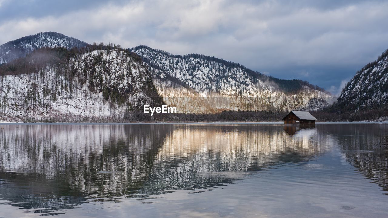 Scenic view of lake by snowcapped mountains against sky