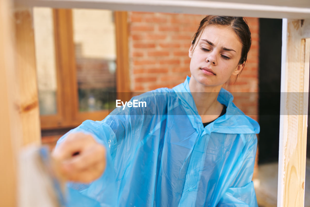 portrait of young woman standing against window