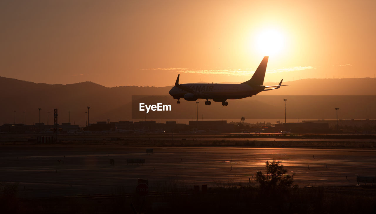 SILHOUETTE AIRPLANE FLYING OVER RUNWAY AGAINST SKY