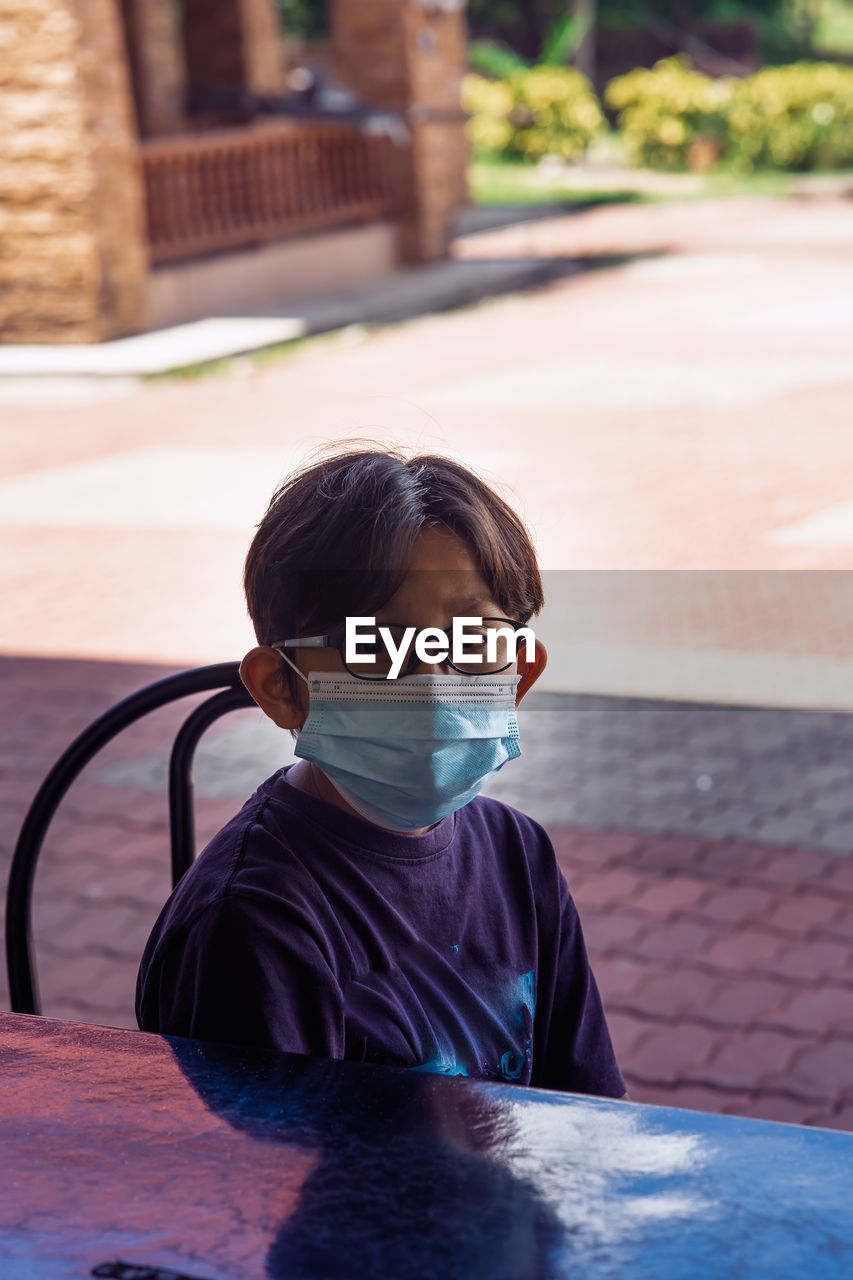 Portrait of boy with mask sitting outdoors