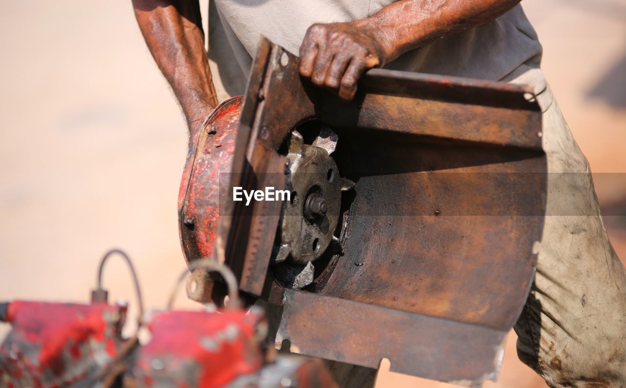 Midsection of man working on rusty machinery