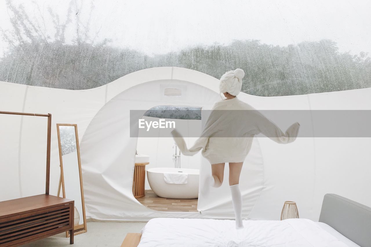 Rear view of woman jumping on bed in tent