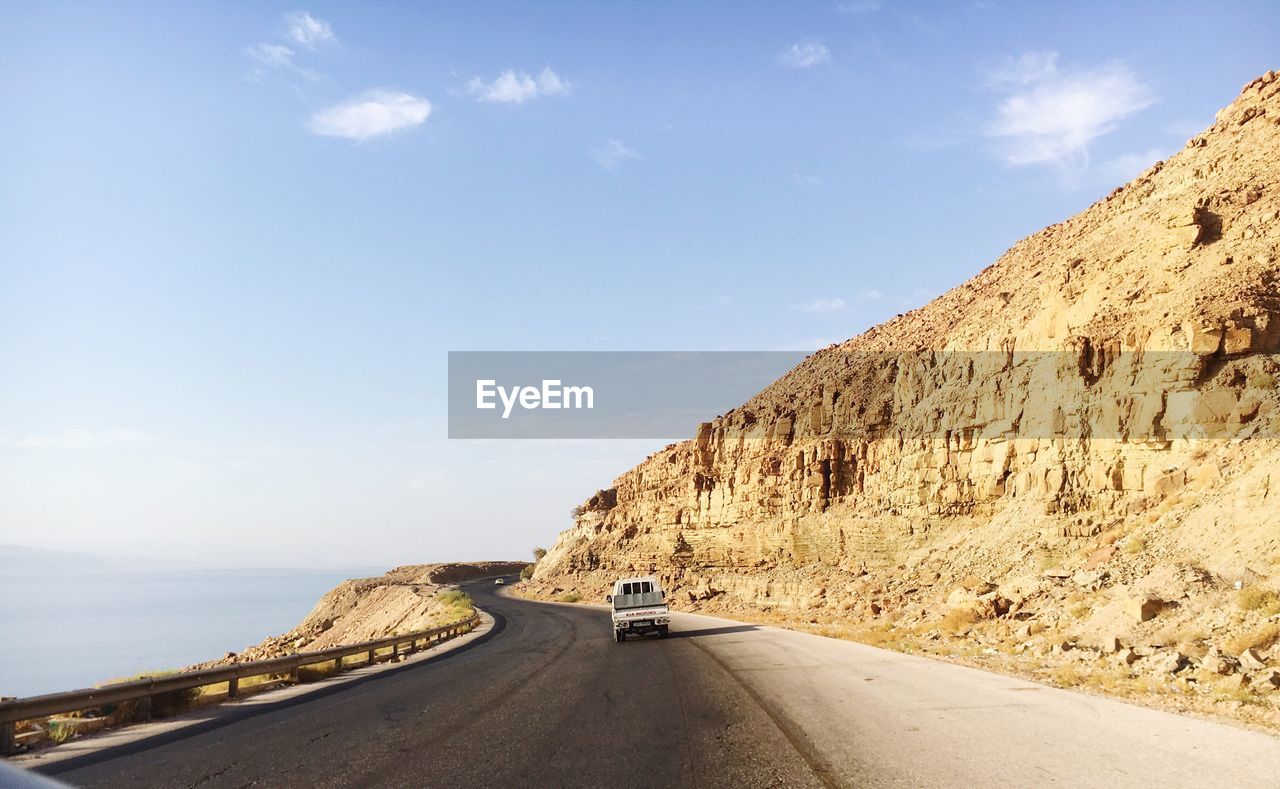 Car on road by cliff against sky