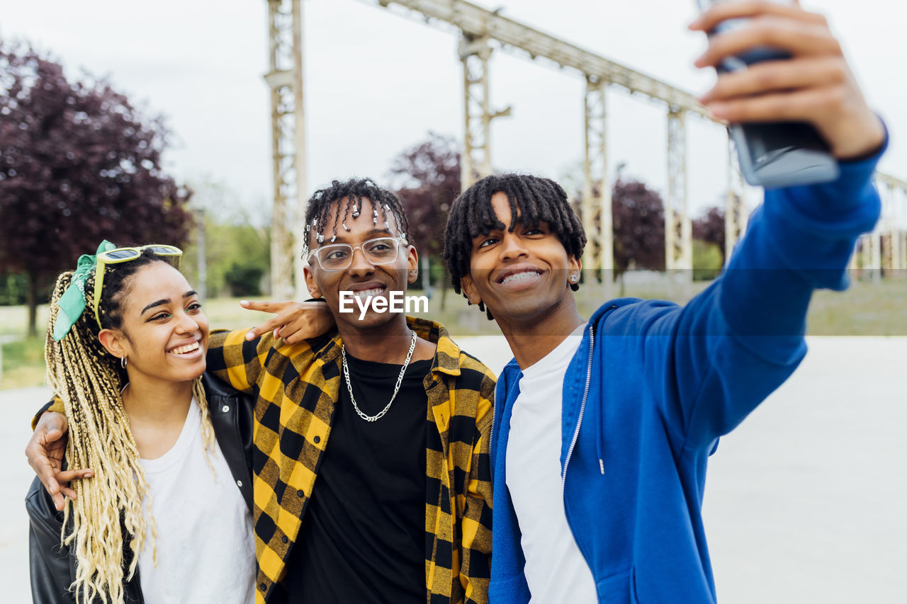 Happy man taking selfie with friends through smart phone