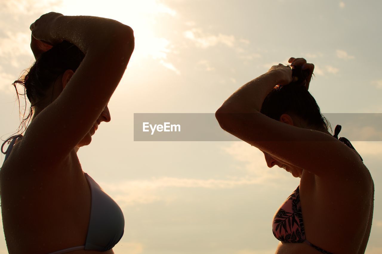 Low angle view of young woman against sky during sunset