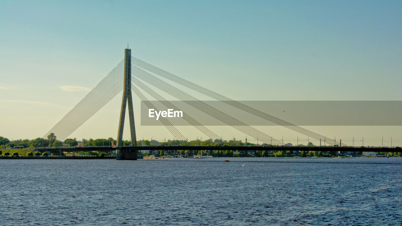 Suspension bridge over river against clear sky