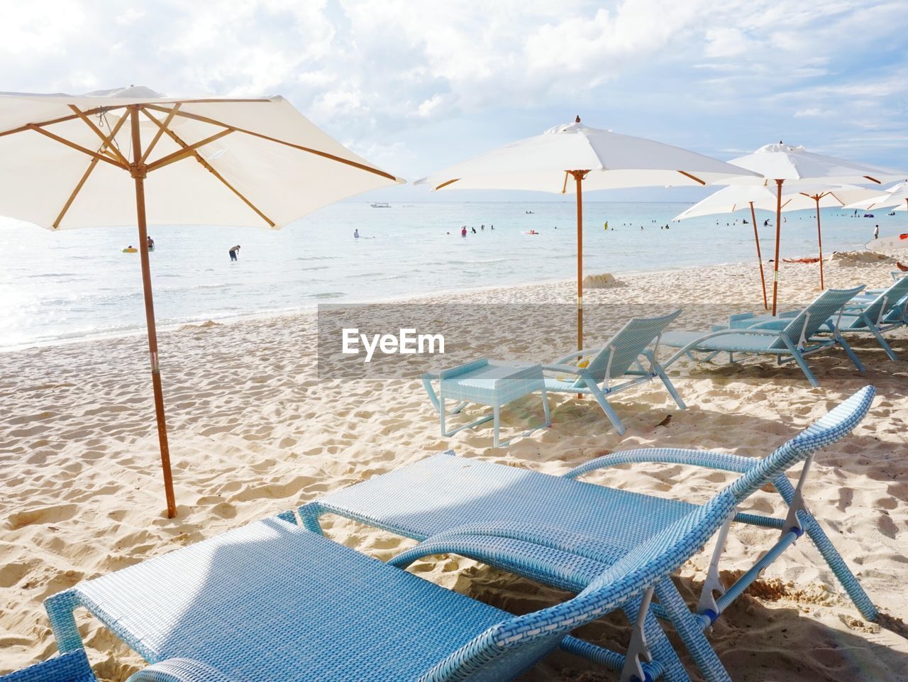 Deck chairs on beach against sky