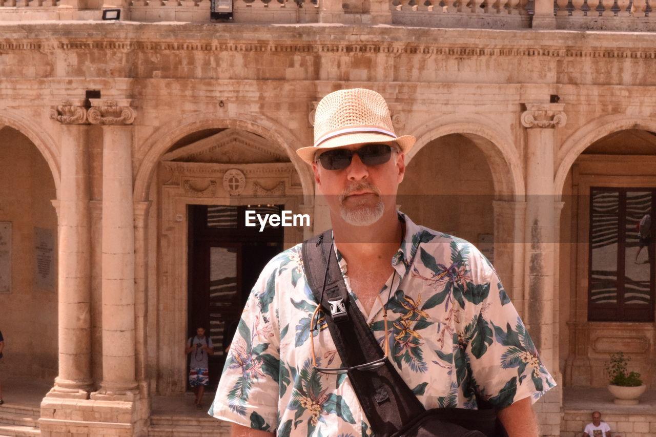 Portrait of senior man standing in front of building