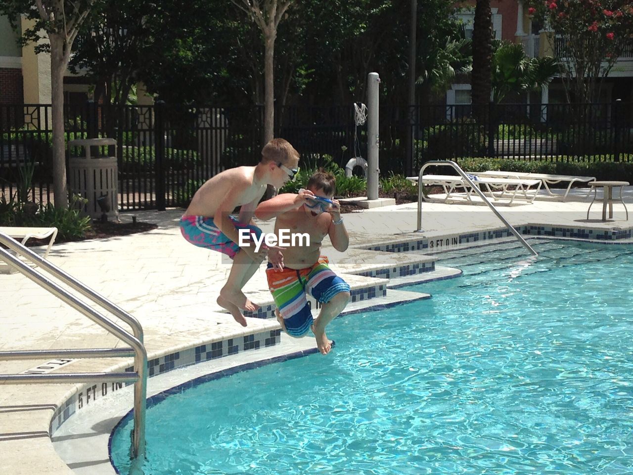 BOY JUMPING IN SWIMMING POOL AT RESORT