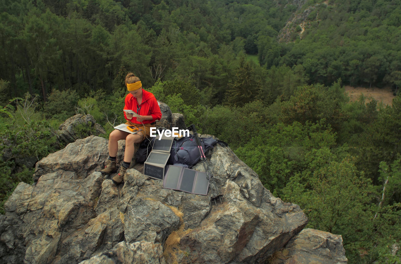Hiker using laptop while sitting on rocky mountain