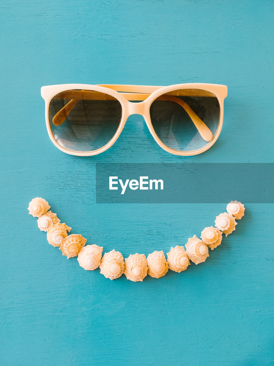 Directly above shot of sunglasses and seashells on blue table