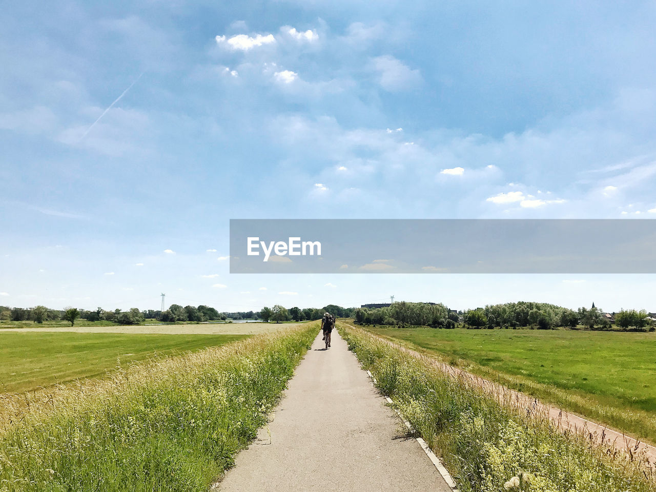 Empty road amidst field against sky