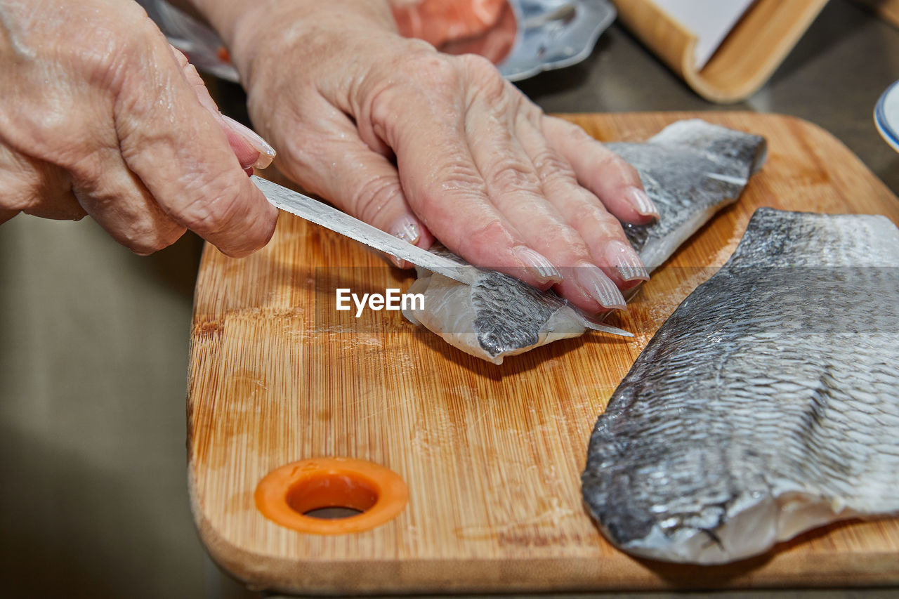 Chef is skinning salmon fillets for cooking