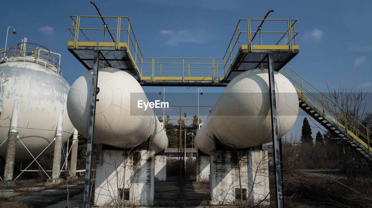 Storage tank at industry against sky