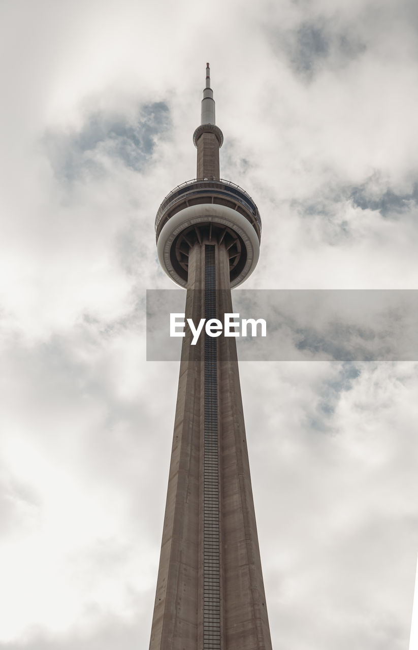 Looking up at the cn tower in toronto, canada against a cloudy sky.