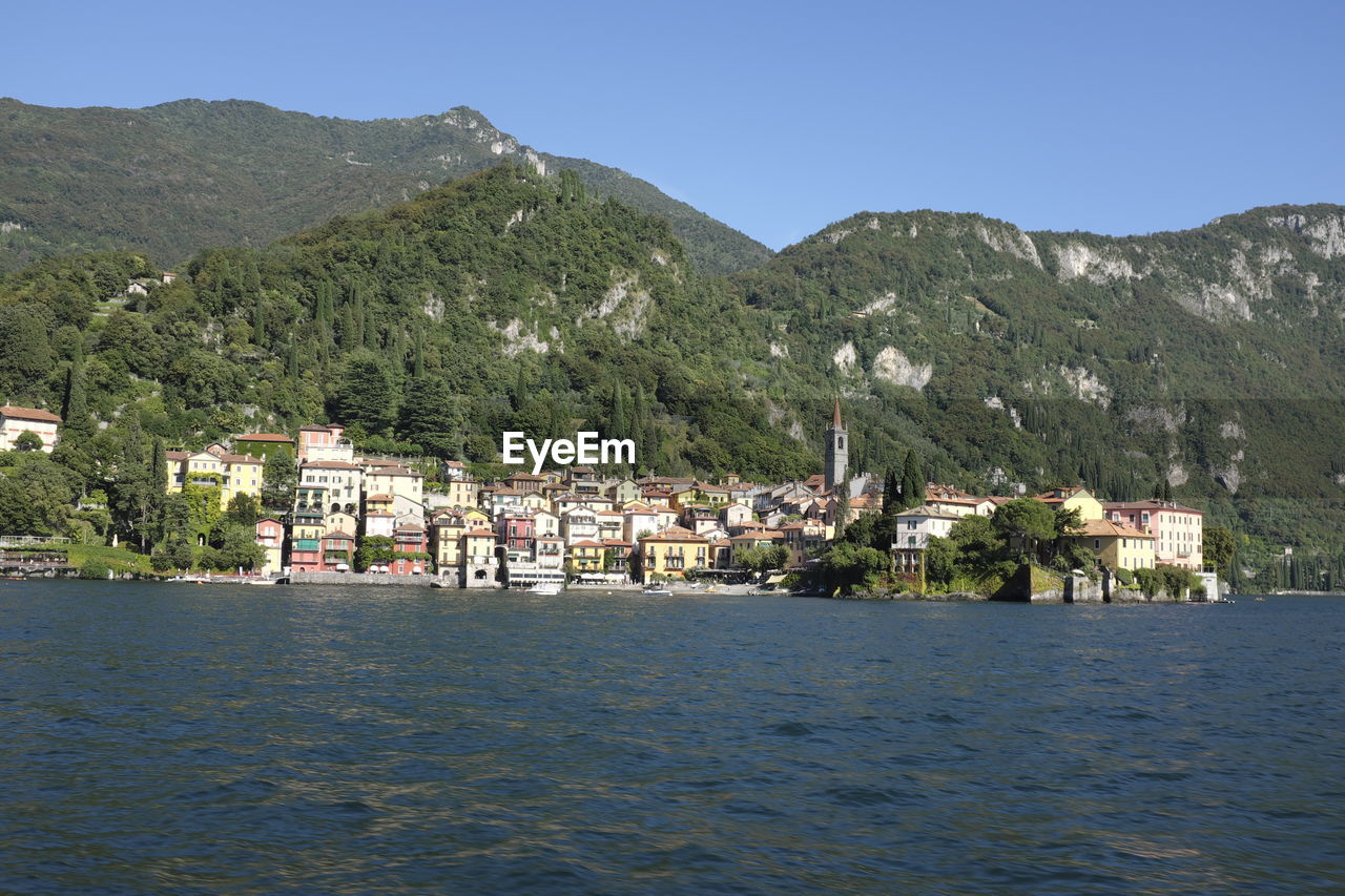 SCENIC VIEW OF SEA AND BUILDINGS AGAINST MOUNTAIN